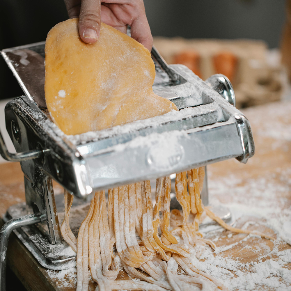 Image of a man inserting pasta dough in a stainless steel pasta maker